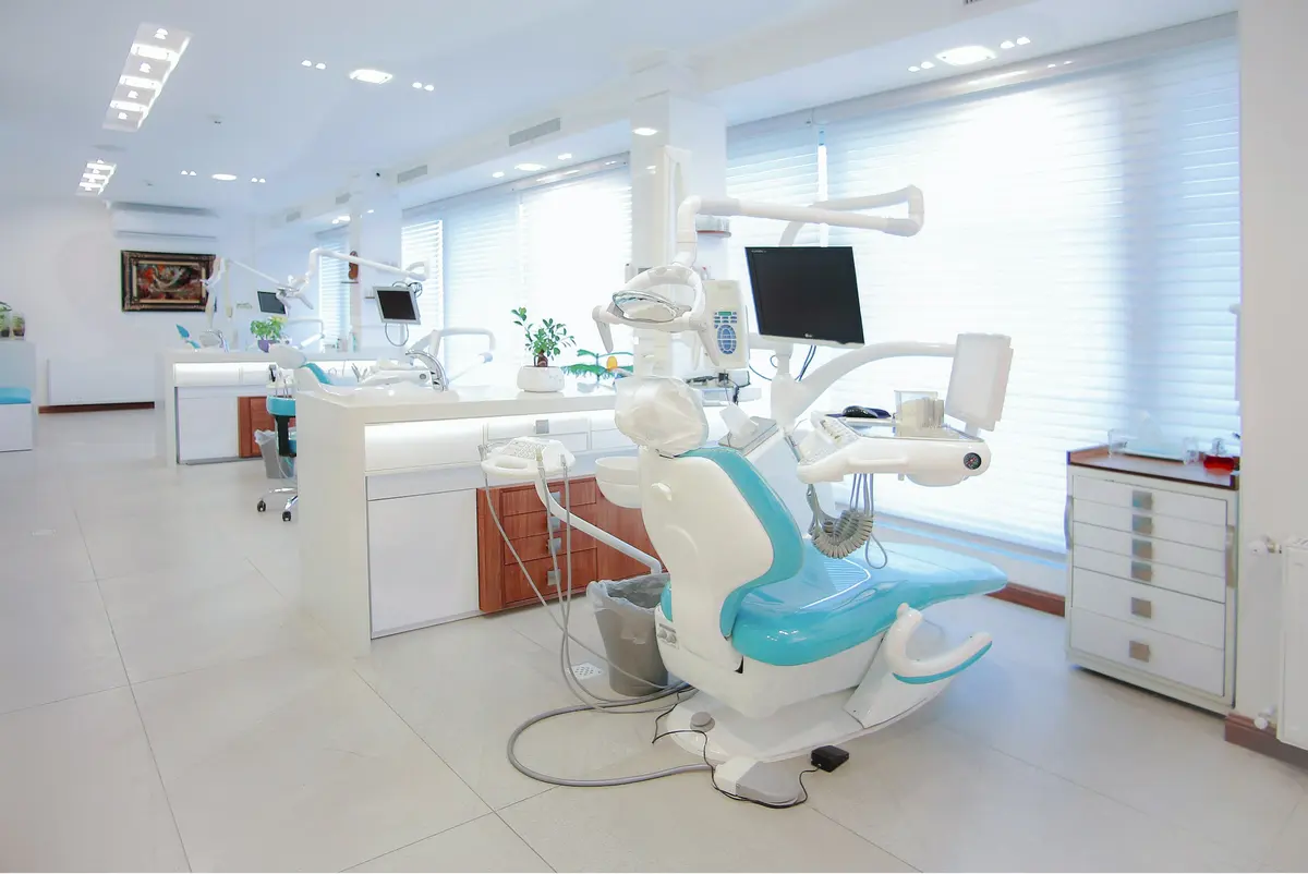 A bright, modern dental operatory with a treatment chair beside a tall window