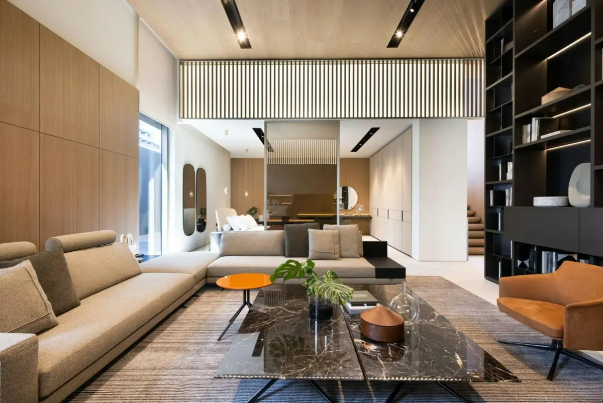 A dark, refined living room with city lights beyond the glass